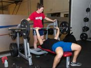 A student spots her friend while bench pressing.
